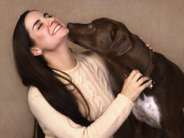 A woman getting kissed by her dog