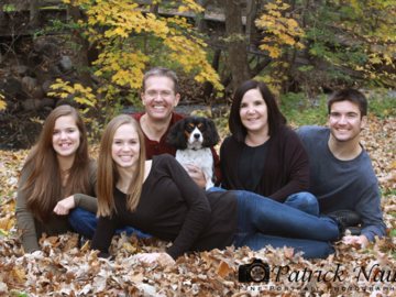 A portrait of a family in the park with their dog