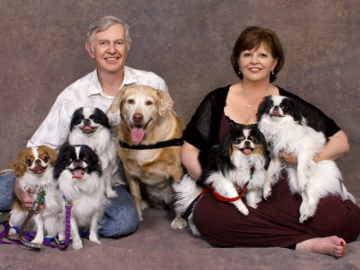A portrait of a couple with their six dogs