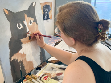 Me working on a pet portrait painting commission of a calico cat.