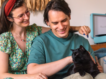 Couple loving their black cat on couch